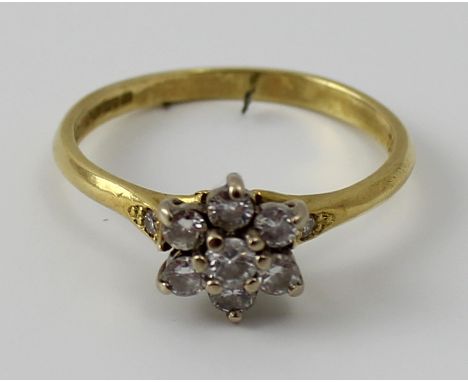 An 18ct yellow gold and diamond seven stone cluster ring with smaller stones set to each shoulder, size M 1/2, approx 2.5g.