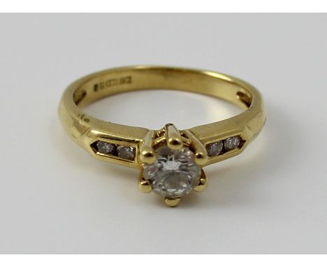 An 18ct yellow gold and diamond ring, the raised central round brilliant cut stone approx 0.2ct flanked by two smaller stones