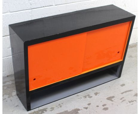 A retro c1950s wall-hanging kitchen cabinet with sliding orange Perspex doors above lower shelf, length 91cm.