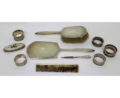 A hallmarked silver dressing table set of mirror, brush and comb, five hallmarked silver napkin rings, a silver manicure nail