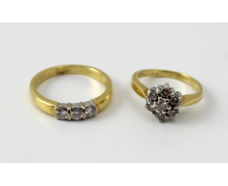 An 18ct yellow gold and diamond cluster ring, and a further three stone ring, size of largest N, approx combined 8g (2).