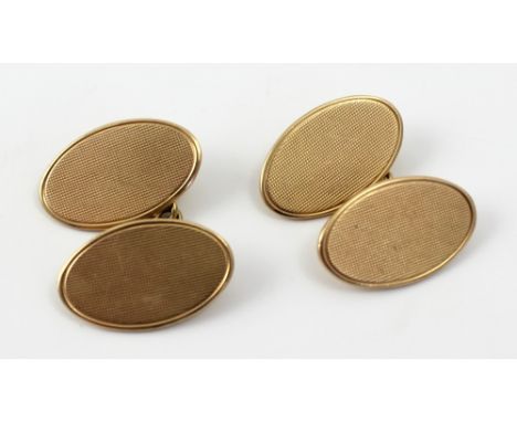 A pair of 9ct gold engine turned decorated cufflinks of oval form with chain link fasteners, approx 8.5g.