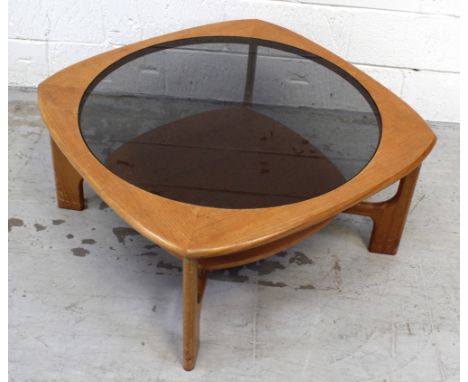 A retro teak coffee table with smoked glass top and lower shelf on spreading supports, diameter 82cm.