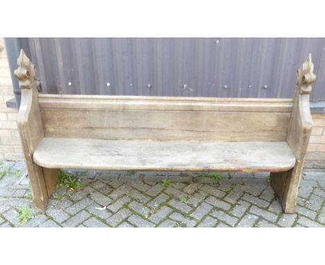 A late Victorian oak and elm church pew, having fleur-de-lis carved capitals, length 180cm