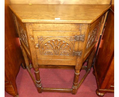 A contemporary joined and floral relief moulded oak single door credence cupboard, raised on ring turned and square cut suppo