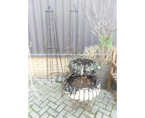 A wrought iron three-tier graduated planter, of scroll form, together with a pair of black painted rodded metal obelisks (3)