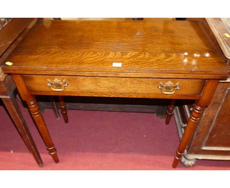 A contemporary oak fold over tea table, having single long frieze drawer, rear gate leg action, raised on turned supports, wi