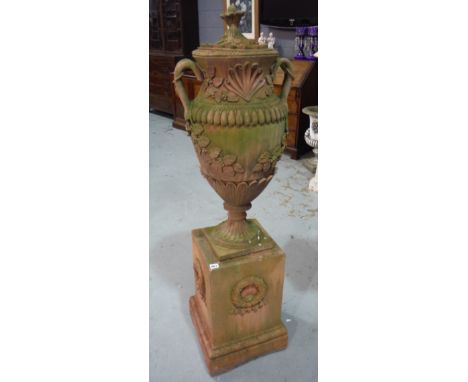 A single classical terracotta terrace urn and cover with pineapple finial above trailing grapes, on a square plinth pedestal 