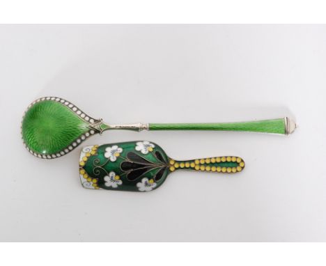 A Soviet silver gilt and enamel caddy spoon, the scoop shaped bowl enamelled with white and yellow flowers above a black styl