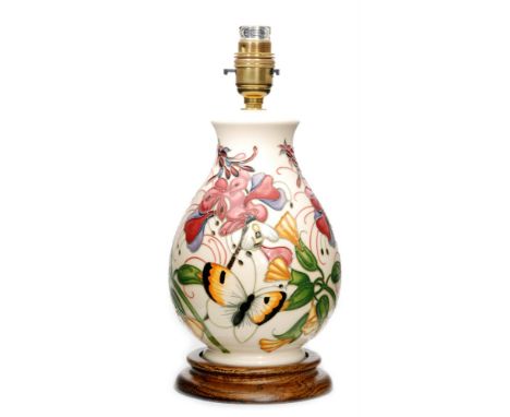 A Moorcroft Pottery table lamp decorated with tube lined butterflies and flowers against a cream ground, marks obscured by af