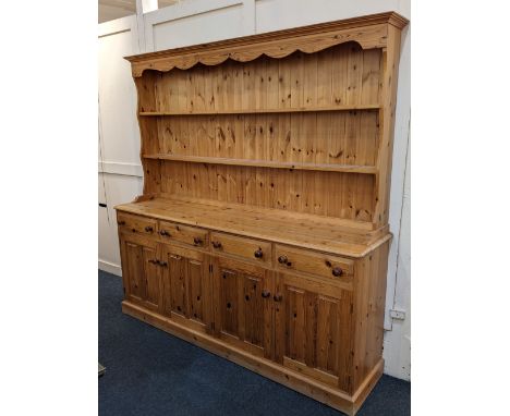 A pine dresser two shelf top with shaped cornice above four drawers and panelled cupboards on plinth base, 195cm