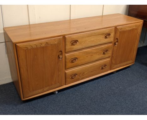 An Ercol light elm sideboard three central drawers with sliding cutlery tray between two cupboards on castors, 156cm