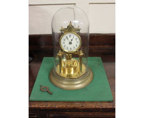 A brass anniversary clock, under a glass dome, on metal base, with key (a/f)