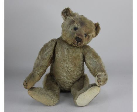 An early 20th century Steiff teddy bear, with button to ear, black eyes, stitched nose, mouth and claws, moveable limbs and g