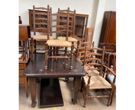An early 20th century oak extending dining table together with a set of five ladder back dining chairs