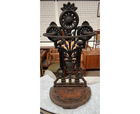 A cast iron stick stand, cast with sunflowers and a vase