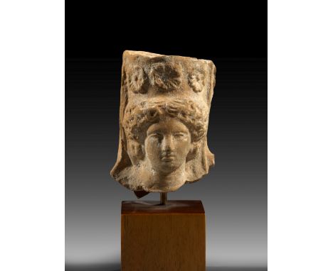 Kopf einer jungen Frau mit Polos. Magna Graecia, 4. v. Chr. H 6,6cm und mit Sockel 9,8cm. Einseitig ausgeformt mit Kaltarbeit