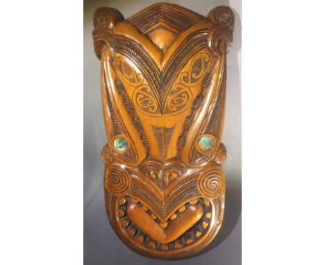 A carved Maori kauri wood paddle with traditional carved design and Mother of Pearl roundel inlays H151cm and a large carved 