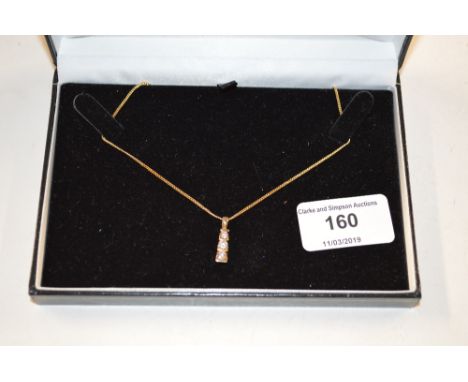 A 9ct gold and three stone diamond pendant hung to a fine link chain 