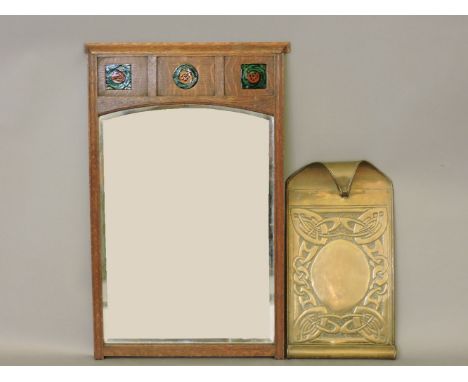 An Arts and Crafts brass wall plaque, and an oak framed mirror set with three porcelain roundels