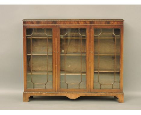 A 20th century mahogany display cabinet, with three astragal glazed doors on bracket feet, 136cm wide