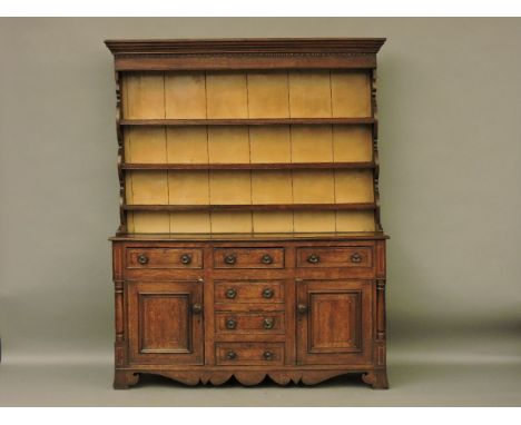 A George III oak dresser, the boarded plate rack back over the base, with central bank of drawers flanked by cupboard doors a