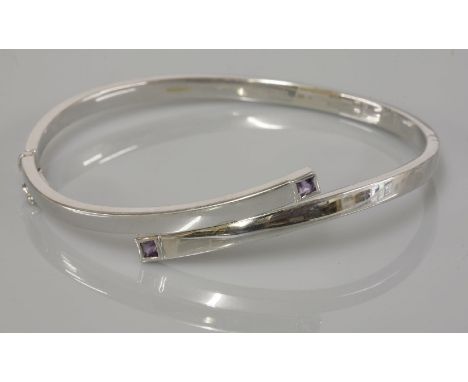 An Italian white gold crossover bangle, set with square cut amethysts, marked 375