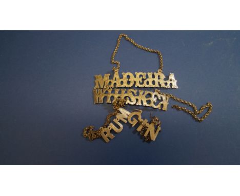 Four unmarked metal decanter labels, for Madeira, Rum, Gin, and Whiskey, largest 9cm.