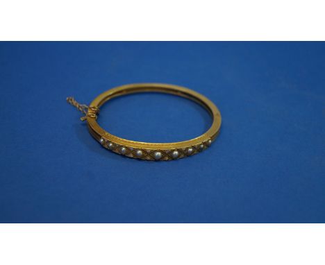 Victorian unmarked hinged bangle, the front set pearls and diamond chips.