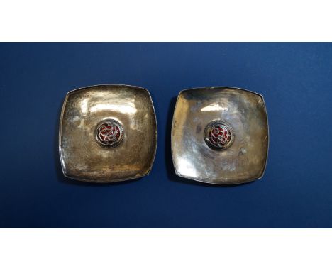 Omar Ramsden & Alwyn Carr, a pair of Arts & Crafts hammered silver pin dishes having central red enamel boss decorated entwin