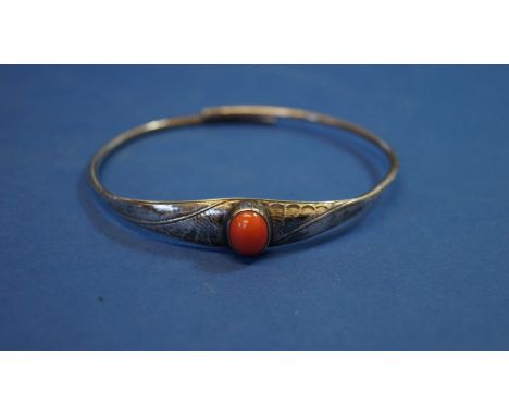 A white metal bangle set oval cabochon coral.