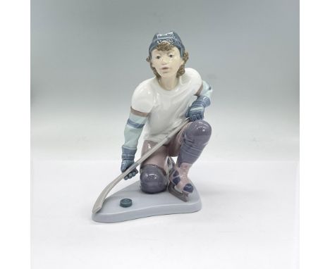 Glazed porcelain figure of a young man on one knee holding his hockey stick. Lladro backstamp. This item has its original box