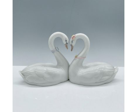 Hand made glossy porcelain, modeled as two lovely swans in a heart pose. Lladro backstamp. Artist: Jose PucheIssued: 1999Dime