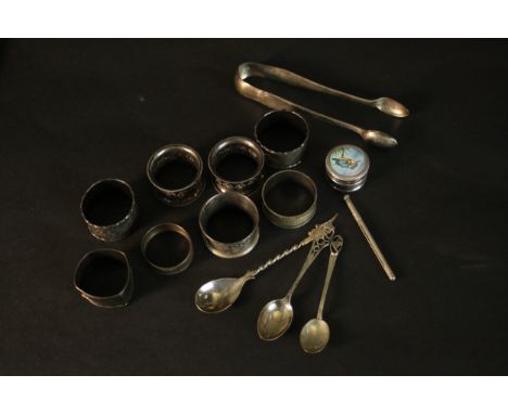 A collection of silver, including a pair of sugar tongs, various napkin rings and a silver and enamel kingfisher pill box. Va