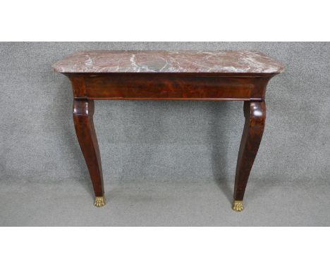 A continental Empire style flame mahogany console table with a marble top on cabriole legs with gilt metal paw feet. 