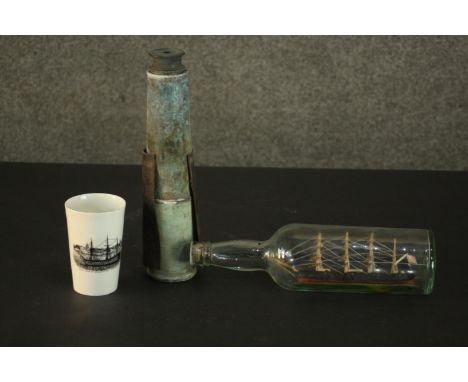 A carved and painted ship in a bottle along with a telescope and a transfer printed ship design ceramic cup. L.30cm (largest)