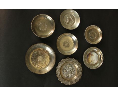 A collection of various silver and white metal dishes, including four with world coins, a hand painted porcelain hunting scen