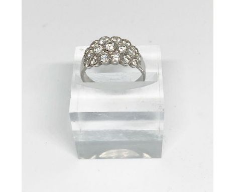 A diamond cluster engagement ring, white metal band (probably platinum), with three rows of small round cut diamonds