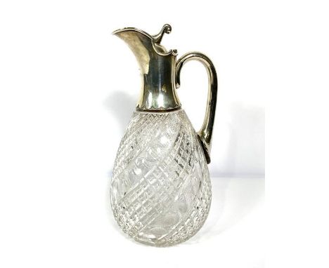 A silver mounted claret jug, hallmarked Birmingham 1919, with a pouring spout, hinged lid and scroll handle, set on a cut gla