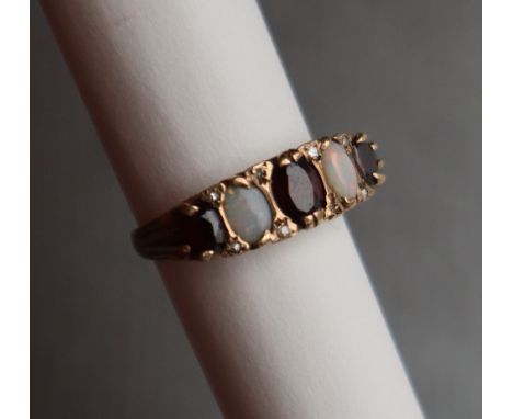 An opal and garnet line ring set with three oval faceted garnets and two opals to a 9ct yellow gold setting and shank, size S