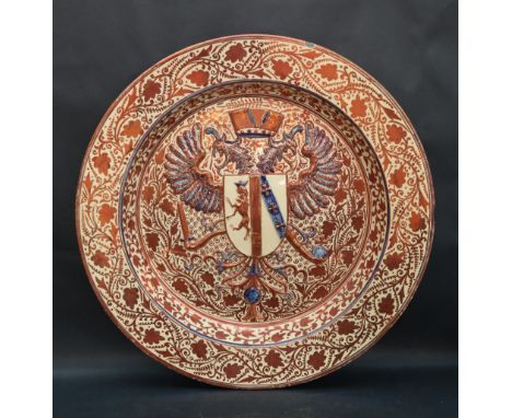 An Hispano Moresque type lustre charger with a crowned double headed eagle and shield to a flower head and leaf decorated rim