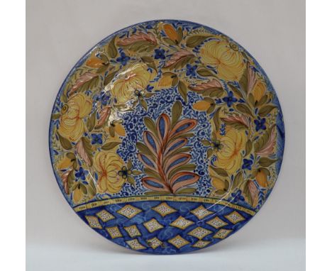 A continental faience charger decorated with leaves and scrolls in blues, greens, oranges and yellows, 41.5cm diameter CONDIT