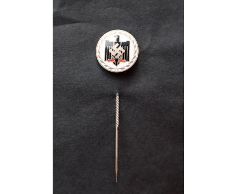 A German pin badge of circular form in white enamel with a central black eagle and white metal swastika, possible relating to