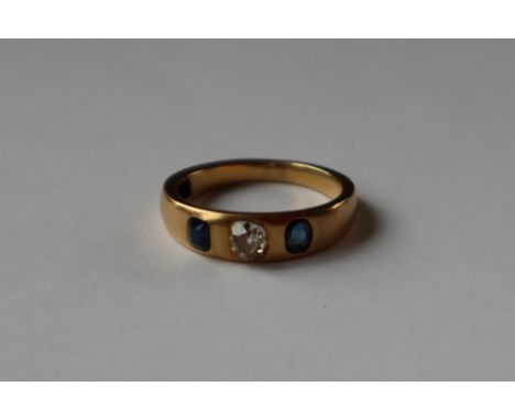 An 18ct yellow gold sapphire and diamond ring, set with a central cushion cut diamond flanked by a pair of oval faceted sapph