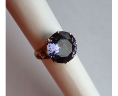 A 14ct gold dress ring with a purple circular faceted stone possibly a purple sapphire, 15mm diameter to claw setting and sha