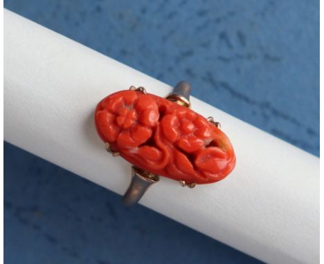 A coral ring, with a central carved panels of flowers and leaves to a 9ct yellow gold setting and shank, size H, approximatel