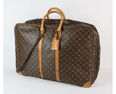 A LOUIS VUITTON large travel bag/suit carrier with luggage label, long strap and padlock (No key but these can be obtained) C