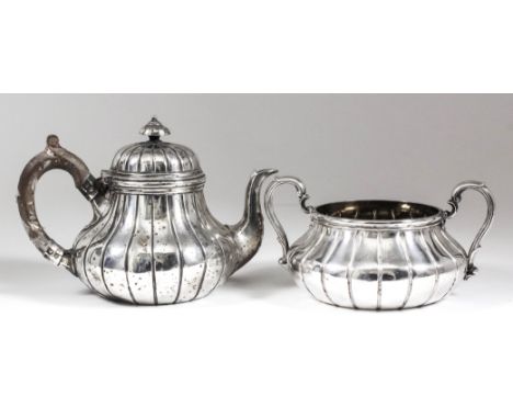 A Victorian silver circular tea pot of bulbous reeded form, the domed cover with turned finial, with composition C-scroll han