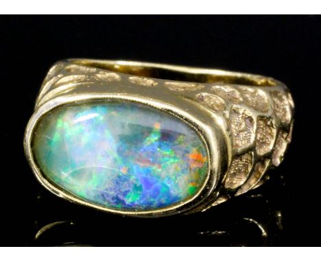 An 18ct gold mounted opal ring set with oval doublet opal (approximately 3ct), and with textured mounts (size L+ - gross weig