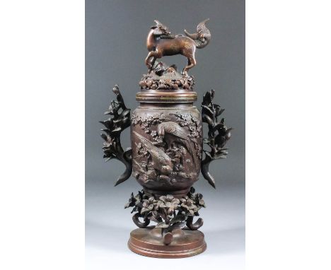 A Chinese brown patinated two-handled koro and cover with deer pattern finial, the body cast in bold relief with birds on flo